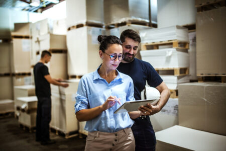 Twee collega's bekijken de planning op een tablet in een logistieke werkomgeving