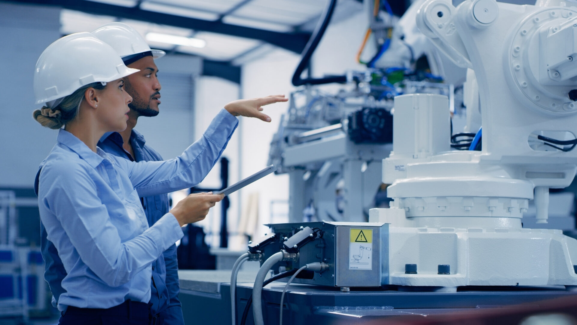 Twee medewerkers werken met een tablet bij een industriële installatie in een technische werkomgeving